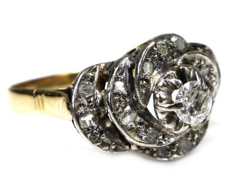 An unmarked yellow gold diamond engagement ring, the brilliant cut stone approx 0.2ct, 3.5 by 2.5mm, surrounded by a swirl of