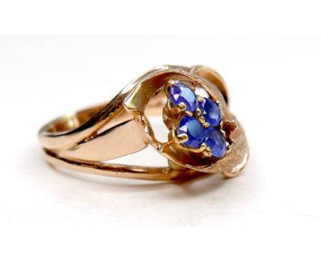 A gold dress ring in the form of a flower, set with four small cornflower blue sapphires, marks rubbed, size M, 5.3g. 