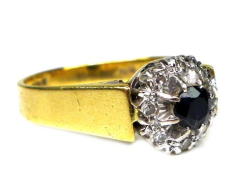 An 18ct gold, sapphire and diamond ring, the central dark sapphire of approximately 3.5mm diameter and surrounded by eight il
