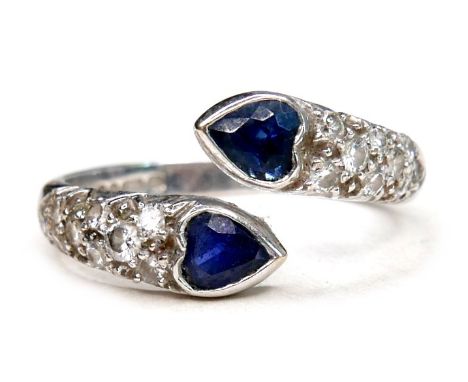An 18ct white gold sapphire and diamond ring, the two heart shaped blue sapphires, each 4.5 by 3.5mm, flanked by nine diamond