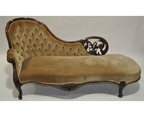 A 19th century Victorian carved mahogany framed chaise,with button back upholstery, carved & pierced panel, raised on scrolle