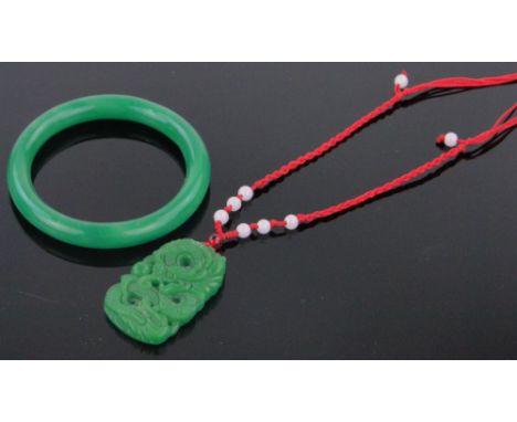 A modern Chinese relief carved jade pendant on silk cord,and a green jade bangle, (2).