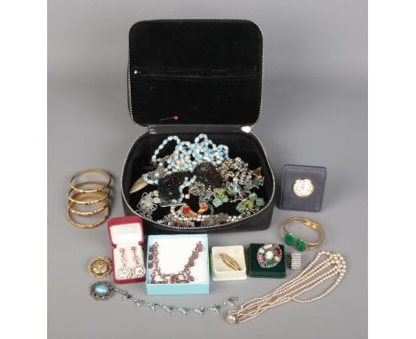 A black dressing case contains vintage boxed and loose jewellery, including necklaces, a table clock, brooches, bracelets, ea