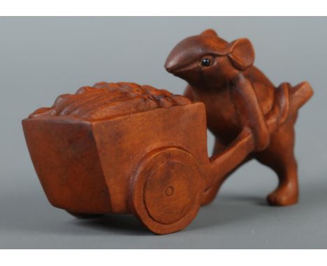 A hand carved hardwood netsuke formed as a mouse pushing a cart, signed to base.