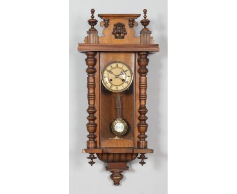 A Vienna style wall clock, with bobbin detailing and Roman Numeral dial. Chiming on a coiled gong. Height: 80cm.