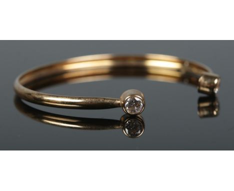 A 9ct Gold child's bangle, set with a paste stone to both cuffs. Total weight: 1.9g