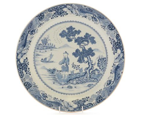 A large Chinese export blue and white charger, Qianlong, decorated in underglaze-blue with a figure with arms folded standing