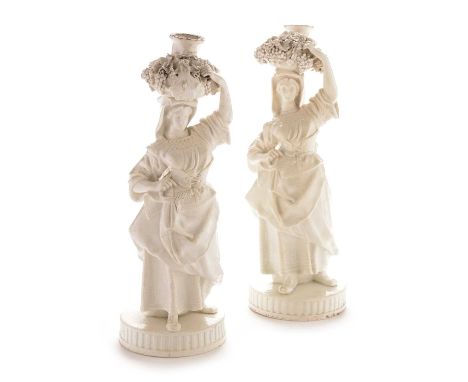 A pair of Stevenson and Hancock, King Street, Derby candlestick figures in the form of continental grape pickers, in the whit