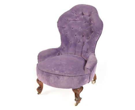 A Victorian mahogany nursing chair, upholstered in lilac fabric, the shaped deep button back above a padded seat and raised o