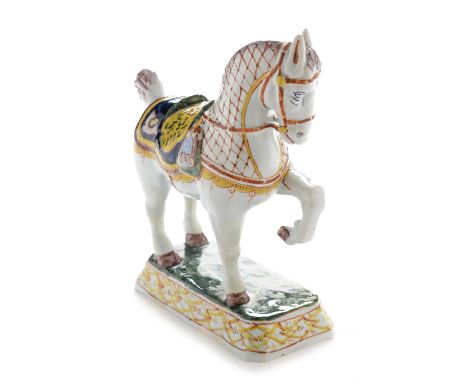 A mid 19th Century Dutch Delft model of a ceremonial horse, painted in yellow, manganese, blue and green, on canted rectangul