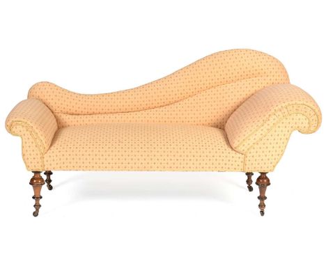 A late Victorian chaise longue, the arched back and scroll over ends above a sprung seat raised on oak turned inverted cup le