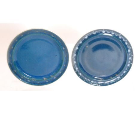 Ruskin Pottery - Two souffle glazed footed saucers each decorated in a mottle blue with a hand painted garland to the border,