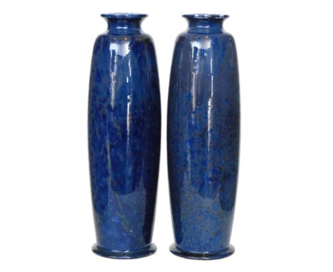 Ruskin Pottery - A pair of souffle glaze 'rolling pin' vases each decorated in a mottled blue with darker speckling creating 