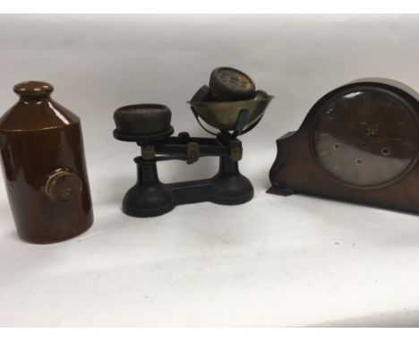 A collection of items to include a Smiths mantle clock, a set of scales and an old hot water jar.