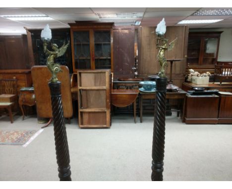 A pair of Mahogany standing lamps topped with brass light bulb holders in the shape of a feminine creature with a tail and wi