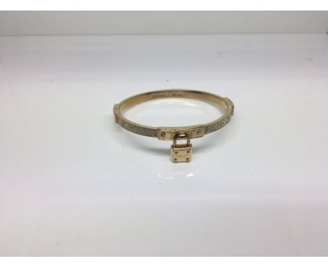 A Michael Kors ladies rose gold plated bangle with padlock detail and inset with cubic zirconia, boxed with pouch and booklet