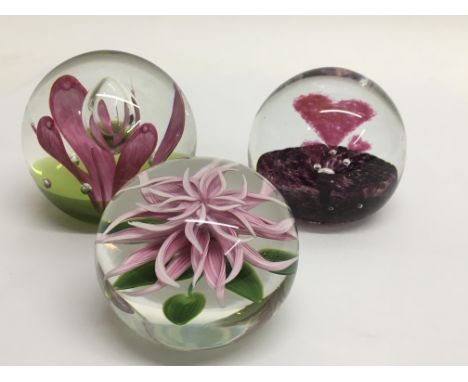 Three paperweights comprising a 1990 Lundberg Studio pink flower, a Scandinavian Holbury heart weight and a Caithness open fl