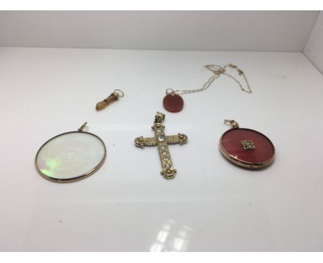 A 9ct gold cross set with stones, a red jade pendant on a 14ct chain, a pendant in the shape of s hsnd with gold, a 9ct pictu
