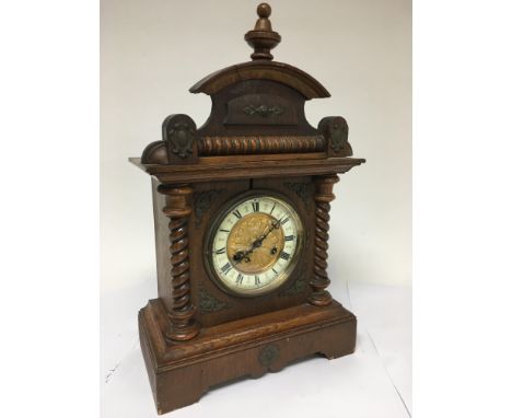 A mahogany cased 8 day mantle clock with barley twist supports and decorative dial.