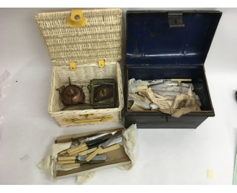 A small metal trunk and basket containing cutlery and metalware