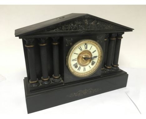 An 8 day slate mantle clock with Corinthian column supports and decorative frieze to the top.