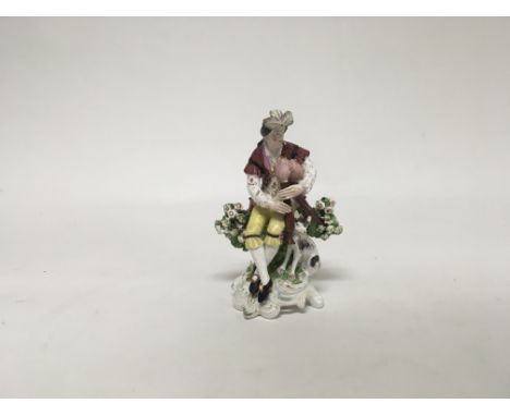 A derby figure of a gentleman sitting in some foliage playing an instrument with his dog by his side. Marks impressed on base