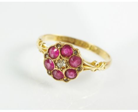 An early 20th century 18ct gold ruby and diamond floral cluster ring, designed as a central old cut diamond claw set within a