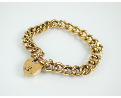 A yellow metal hollow curb link bracelet, the heart shaped padlock clasp stamped '9ct', with attached safety chain, weight 18