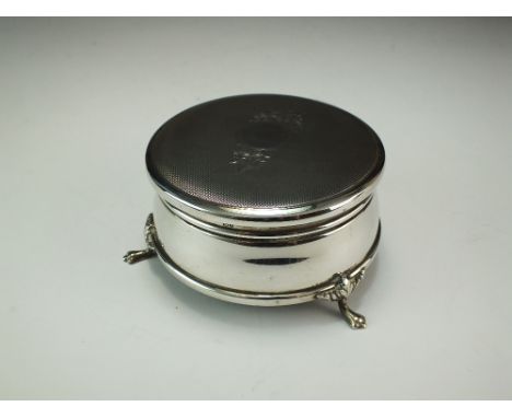 A silver mounted trinket box, B & Co, Birmingham 1976, of circular form with engine turned cover and raised on three paw feet