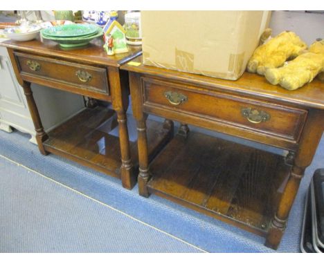 A pair of reproduction oak two tier lamp tables having single inset drawers 