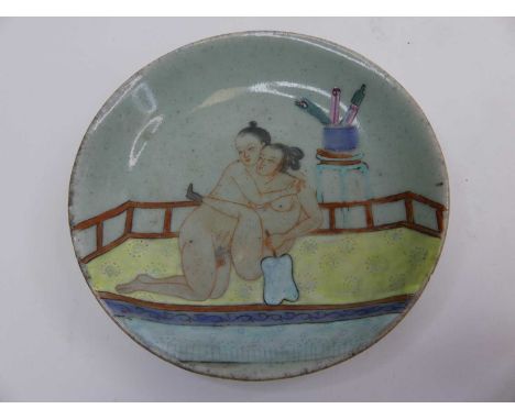 A Chinese celadon glazed dish, enamel decorated with an erotic scene, dia.13cm