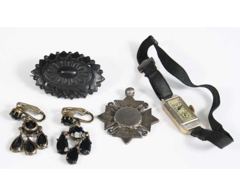 A carved Whitby jet brooch; together with a silver pendant medallion; pair of base metal and jet set ear pendants; and an Art