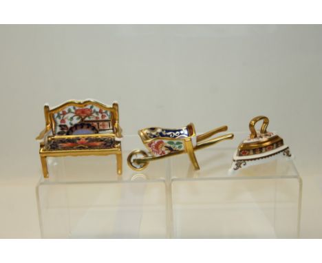 Group of three miniature Royal Crown Derby items to include wheelbarrow, flat iron and bench