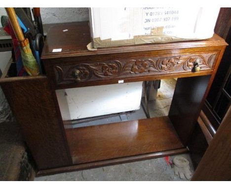 A 1930s carved oak hall stand with a drawer flanked by a stick stand, over an open shelf 