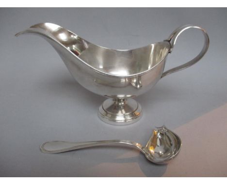An Italian silver sauce boat with a scrolled handle on a pedestal foot and a similar sauce ladle, stamped 800 and a label Ian