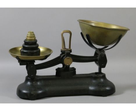 A set of cast iron and brass kitchen scales along with a set of graduated weights.