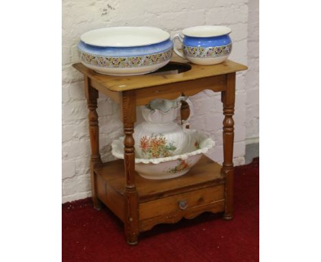 A pine washstand raised on turned supports with single drawer, along with assorted ceramic jugs and bowls.