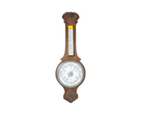 An early 20th century circa. 1920's oak cased aneroid banjo barometer having carved palmette motif to top and Tudor rose to b