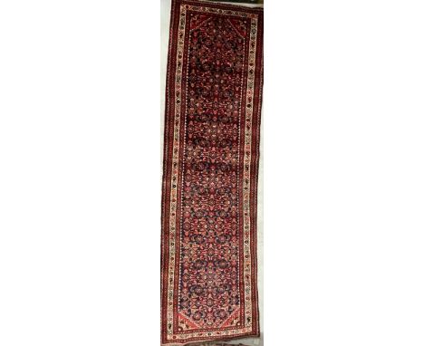 A 20th century Persian Islamic North West Malayer floor carpet runner rug having a central panel with repeating foliate patte