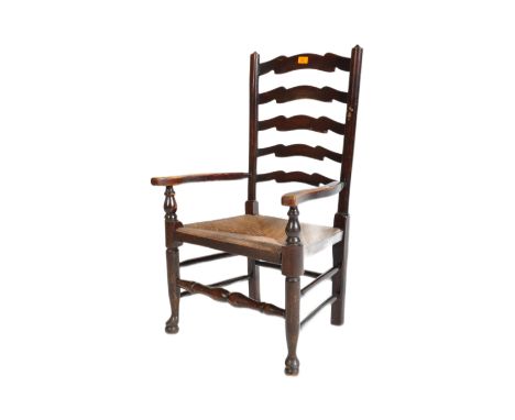 A 19th century North Country oak ladder back woven rush seated elbow chair with spindles to the top of turned supports raised