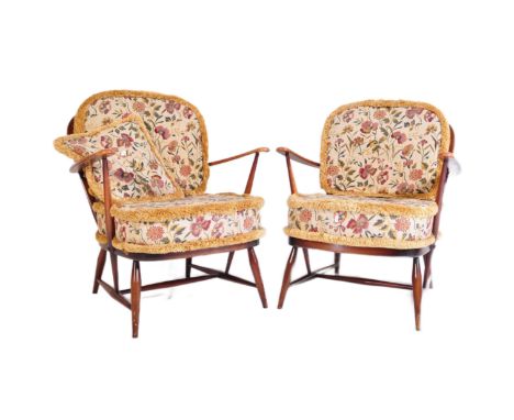 A pair of mid 20th Century dark beech and elm Ercol Windsor low arm chairs. Having a curved spindle back rest with straight a