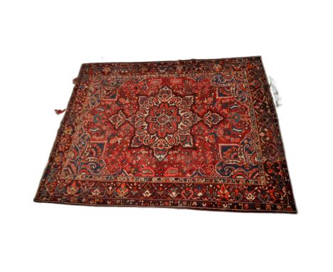 A large early 20th Century Persian floor carpet rug having a large central medallion on red ground with repeating geometric b