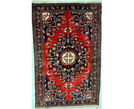 A 20th century North West Persian Islamic Tafresh floor rug carpet having a central shaped medallion in reds, black &amp; cre