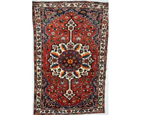 A 20th century Persian Islamic Bakhtiar floor rug carpet having a central floral shaped medallion in polychrome tones within 