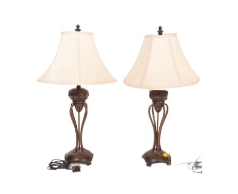 A pair of Art Deco style table lamp lights. Having a cream tapering material lamp shade, with a bulbous decorated pierced cen