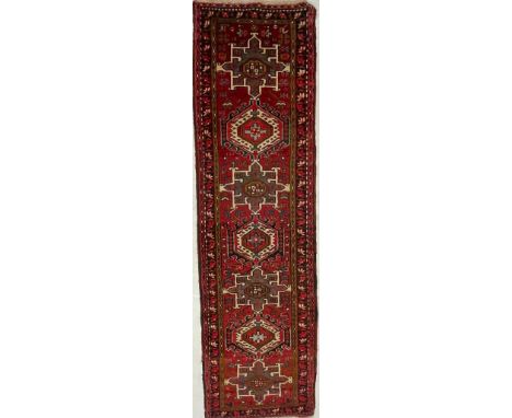 A 20th century North West Persian Islamic Heriz floor rug carpet runner having a series of repeating geometric pattern to cen