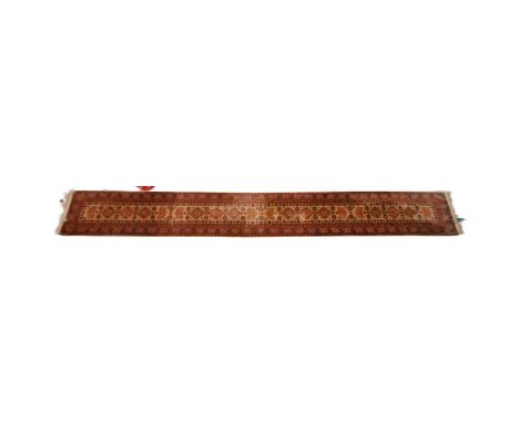 A large early 20th Century Persian floor carpet runner rug. Central cream ground with repeating geometric panels to the borde