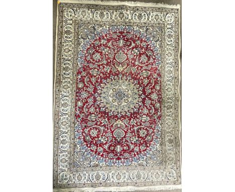 A vintage late 20th century Persian Islamic Nain floor carpet rug having a central sun shaped medallion enclosed in a red gre