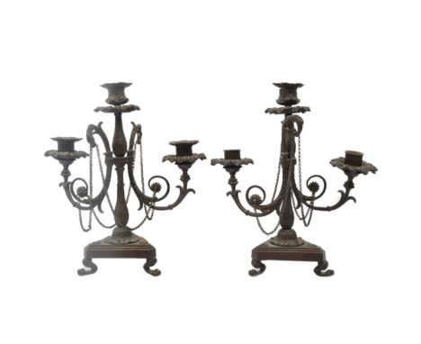A pair of 19th century Victorian bronze candelabra having cast acanthus leaf holders over arms modelled in the form of flamin