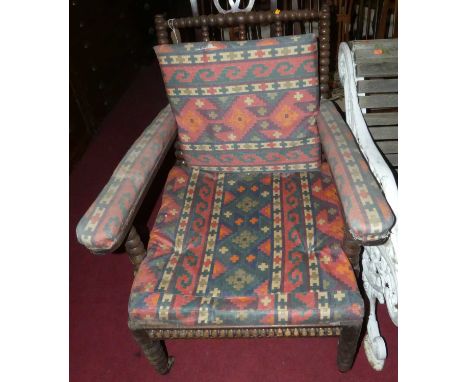 A Victorian bobbin turned oak armchair, having cushioned upholstery to webbed seat, width 70cm